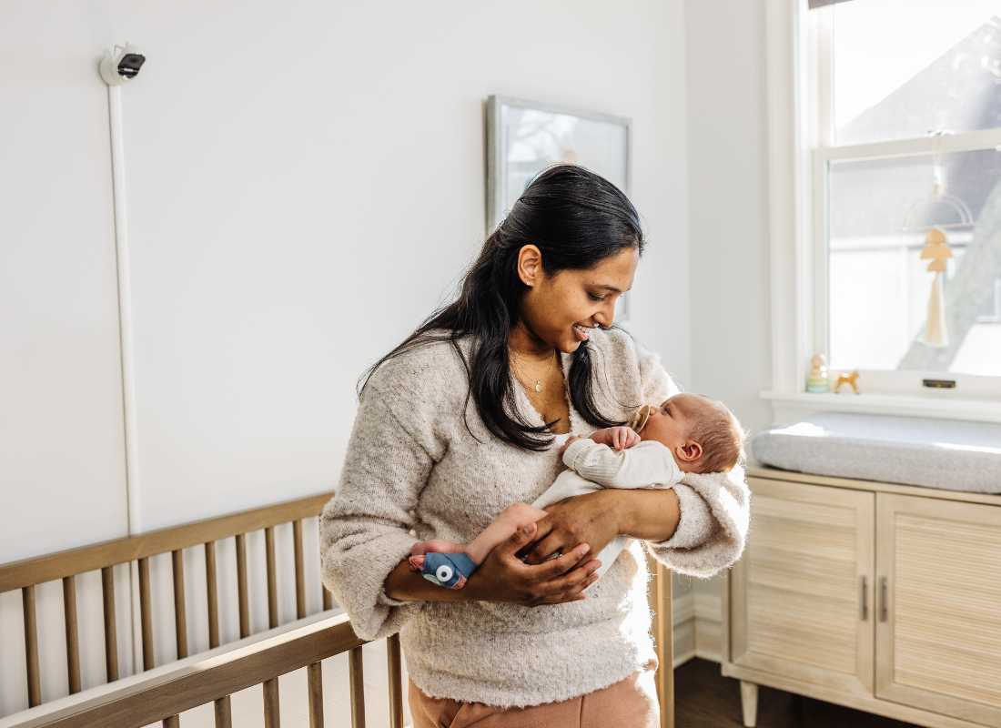 Mum hold's baby wearing an Owlet Midnight Blue Dream Sock