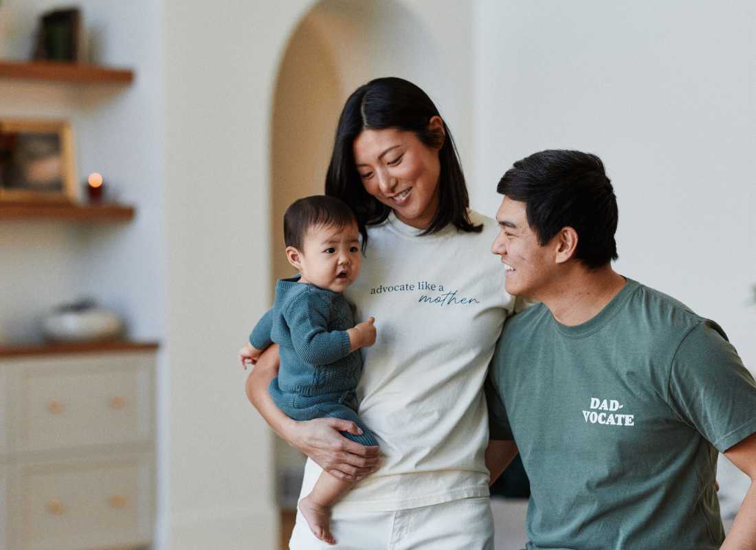 Parents in pyjamas hugging and hold a baby